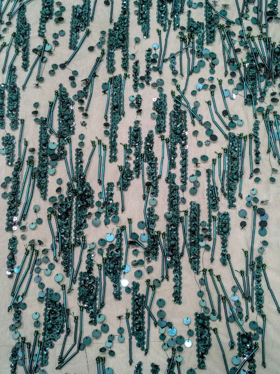 Turquoise round and elongated embellishments forming irregular vertical lines on a pale ground.