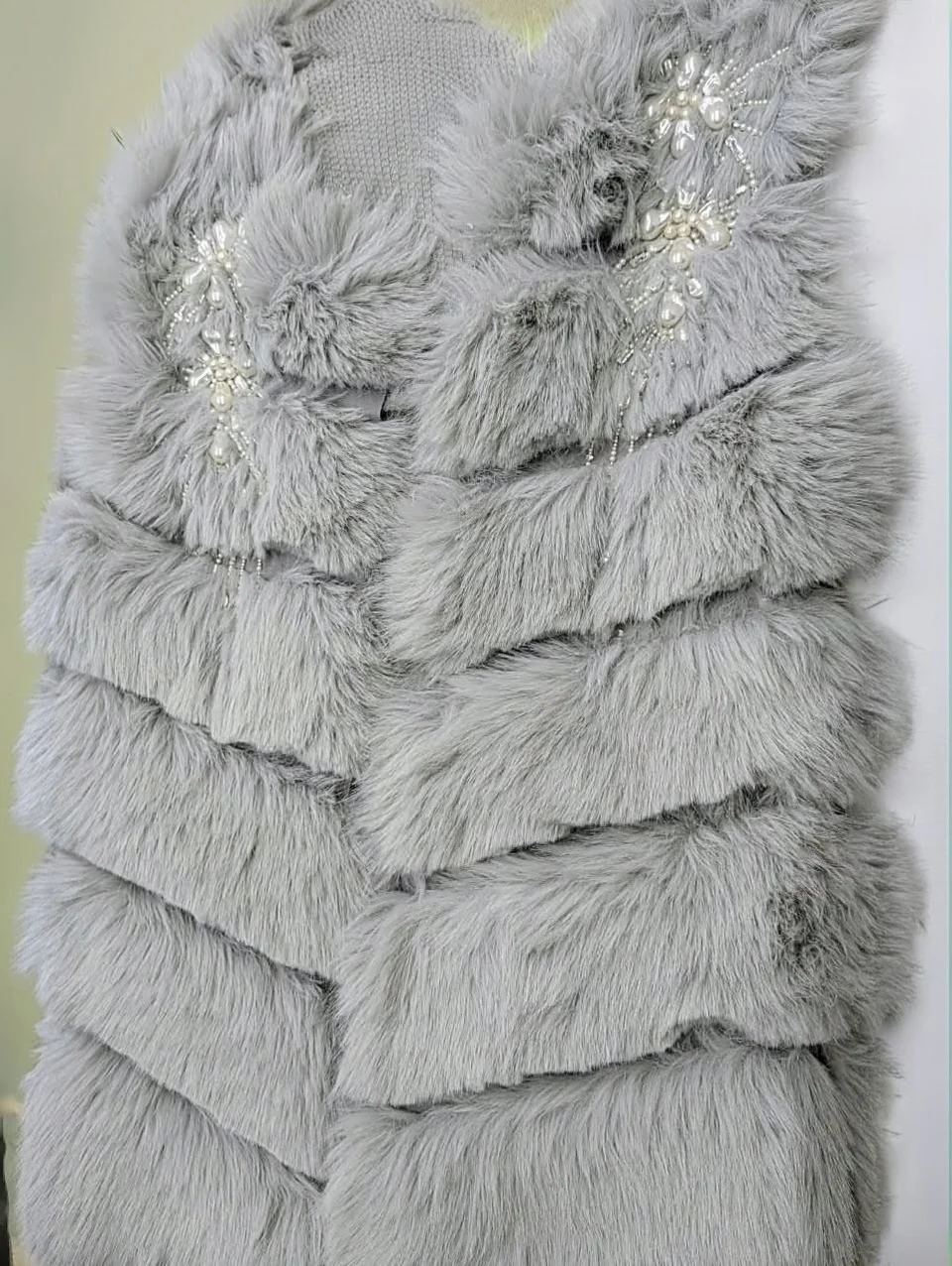 Textured grey vest with pale floral embellishments at both shoulders.