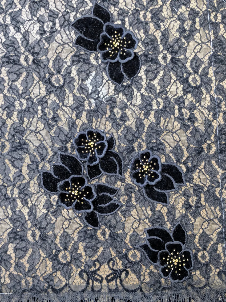 Dark raised flowers with small golden centres on a blue-grey open floral ground.