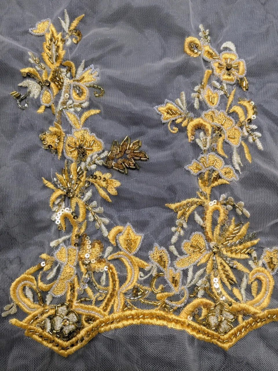 Golden-yellow curling leaves and flowers around an open centre on transparent net.