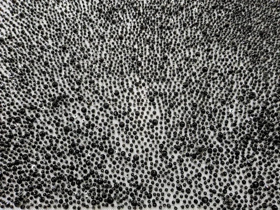 Close-up of dense dark rounded embellishments arranged in flowing, wave-like rows.
