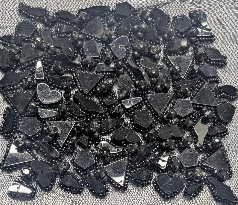 Dense arrangement of glossy dark hearts, triangles and rounded shapes on open net.